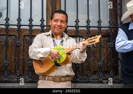 Puebla, Mexiko, lächelnder Mann, der auf der Straße eine kleine mexikanische Gitarre spielt Stockfoto