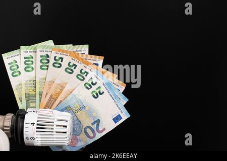 Heizthermostat mit einem Fach aus Euro-Banknoten im Hintergrund Stockfoto