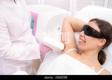 Diodenlaser Haarentfernung, Kosmetikerin entfernt Haare auf schönen weiblichen Achseln, Haarentfernung für glatte Haut, Laser-Verfahren im Beauty-Studio oder Stockfoto