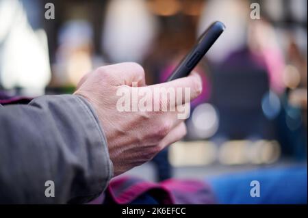 Weiße kaukasische männliche Hand mit schwarzem Handy Stockfoto