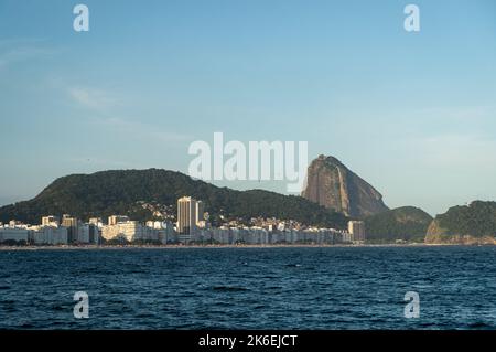 Weiter Blick auf die Copacabana und Leme Strände Küste mit dem hohen Zuckerhut auf der Rückseite, wie vom Fort Copacabana am späten Nachmittag am blauen Himmel zu sehen. Stockfoto