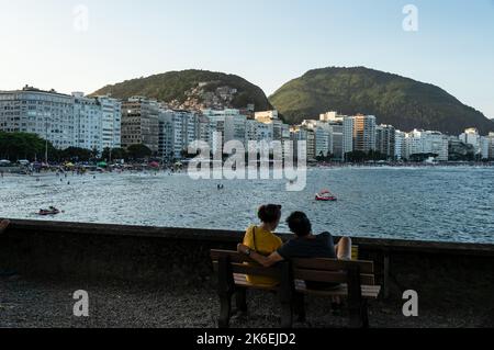 Weiter Blick auf Apartmentgebäude Seite an Seite am südlichen Ende des Copacabana Beach mit Bergen hinten am sonnigen späten Nachmittag unter blauem Himmel. Stockfoto