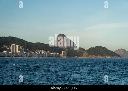 Weiter Blick auf die Copacabana und Leme Strände Küste mit dem hohen Zuckerhut auf der Rückseite, wie vom Fort Copacabana am späten Nachmittag am blauen Himmel zu sehen. Stockfoto