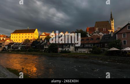 St. Veitskirche und malerische Altstadthäuser am Ufer der Moldau in Cesky Krumlov, Tschechien. Schönes Sonnenuntergangslicht, stürmische Wolken, Stockfoto