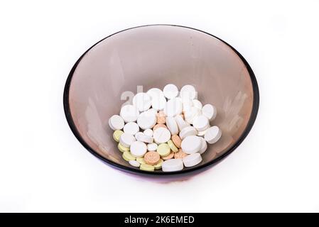 Medizinische, weiß-schwarz-orange Pillen verschütten aus einem weißen Glas auf einem isolierten weißen Hintergrund Stockfoto