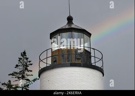 Acadia National Park, Maine, USA. Ein Regenbogen, der aus Nebel und Nebel hinter der Bass Harbor Head Light Station auftaucht, wurde 1858 errichtet. Stockfoto