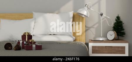 Nahaufnahme, minimales und komfortables Schlafzimmer-Innenraumdesign an den Weihnachtsferien mit Weihnachtsgeschenken auf bequemen Betten, kleinem Weihnachtsbaum und Dekor Stockfoto