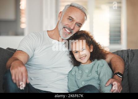 Eine Familie zu sein bedeutet, dass Sie ein Teil von etwas sind. Ein Mädchen, das zu Hause mit ihrem Großvater sitzt. Stockfoto