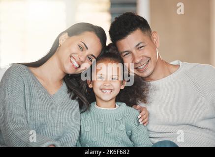 Die Dinge, die wichtig sind, sind Glaube, Familie und Freunde. Ein Mädchen auf einer Couch mit ihren Eltern zu Hause. Stockfoto