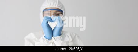Der Arzt in Schutzanzug macht mit den Händen eine Herzbewegung Stockfoto