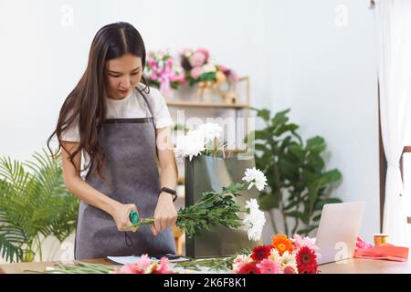Flower Shop Konzept, Weibliche Floristin geschnitten Chrysantheme Stiele mit Schere für Blumensträuße zu machen. Stockfoto