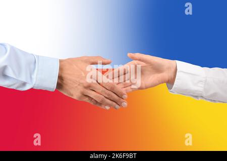 Mann und Frau schütteln sich die Hände gegen die Fahnen der Ukraine und Polens Stockfoto