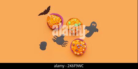 Leckere Halloween Cupcakes und Dekor auf orangefarbenem Hintergrund, Draufsicht Stockfoto