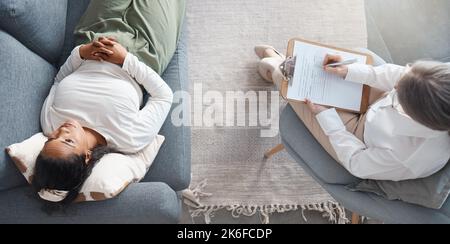 Ihre Probleme sind kleiner, als sie scheinen. High-Angle-Aufnahme einer unkenntlichen Psychologin, die mit ihrer Patientin sitzt und sich während eines Notizen macht Stockfoto