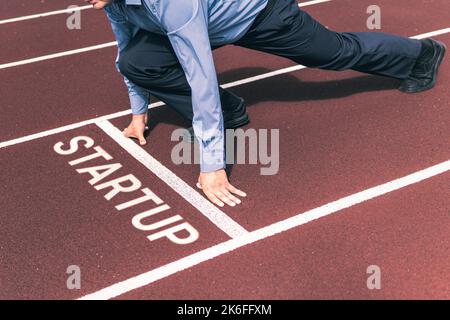 Geschäftsperson, die auf das Startsignal wartet, um auf der Laufstrecke des Wettbewerbs zu laufen. Startup-Unternehmen. Konzept der Beginn einer Karriere. Stockfoto