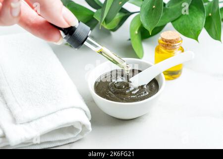 Enreaching schwarzen Ton hausgemachte Maske mit ätherischem Öl. Spa-Behandlungen zu Hause. Hautpflegekonzept. Pflanzliche alternative Kosmetik. Stockfoto