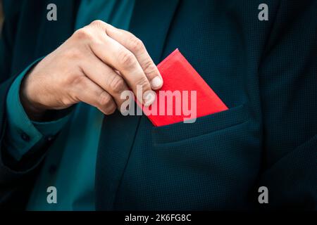 Der rote Personalausweis. Mann Mit Id-Karte. Geschäftsmann in einem blauen Anzug zeigt einen roten Personalausweis oder einen Pass. Die Hand eines Mannes in einem blauen Business-Anzug nimmt ein Stockfoto