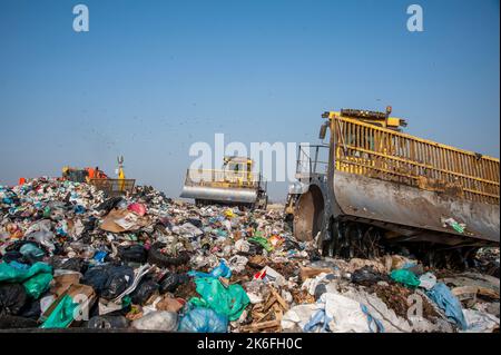 Mülldeponie. Arbeiter mit Lastwagen und Planierraupen arbeiten auf Mülldeponien. Stockfoto