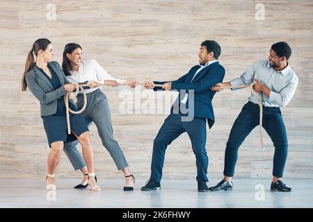 Wer wird diesen Kampf gewinnen? In voller Länge eine vielfältige Gruppe von Geschäftsleuten, die im Büro zusammen stehen und am Seil ziehen. Stockfoto