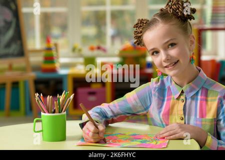 Schönes kleines Mädchen zeichnet mit einem Bleistift auf ein Blatt Papier Stockfoto