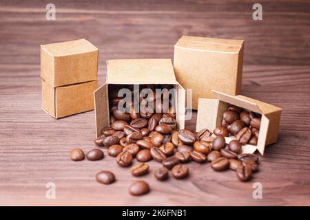 Ein Haufen versiegelter und offener Miniaturkartons mit gerösteten Kaffeebohnen auf einem hölzernen Hintergrund. Röst- und Versandkonzept für Kaffee. Stockfoto