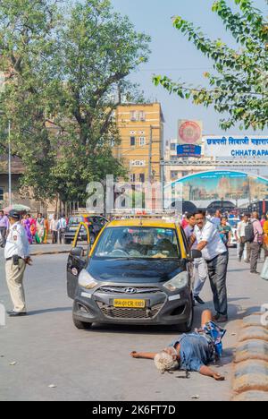 Mumbai, Maharashtra, Südindien, 31.. Dezember 2019: Ein Taxi und ein betrunkener Mann liegen auf der Straße. Stockfoto