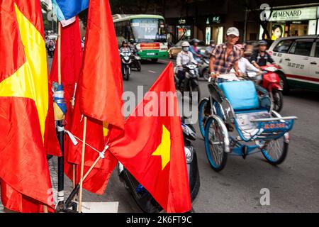 Verkehr und Flaggen auf der Straße im Zentrum von Ho Chi Minh City, Vietnam Stockfoto