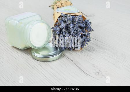 Natürliche handgemachte kosmetische Creme-Glas und getrocknete Lavendelblüten, heller Hintergrund. Bio-Bio-Kosmetik. Anlagenbasis. Stockfoto