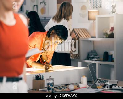 Sie schafft so schön. Eine Geschäftsfrau, die in einem Workshop an Entwürfen arbeitet. Stockfoto