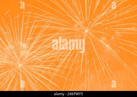 Abstrakter Feiertagshintergrund mit gelbem Feuerwerk gegen Orange Stockfoto