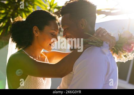 Glückliches afroamerikanisches Paar heiratet, umarmt sich am Hochzeitstag Stockfoto