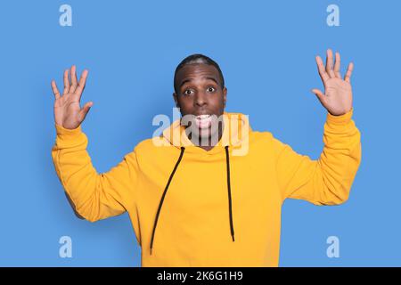 Junger attraktiver Mann, der auf blauem Hintergrund überrascht aussaunt Stockfoto