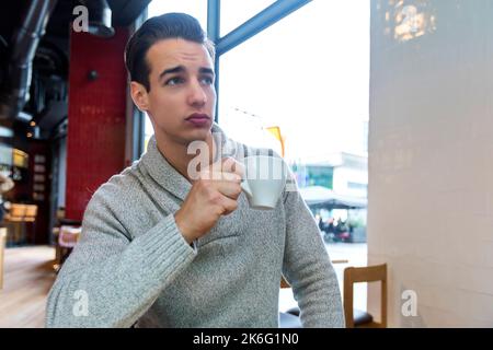 Junger Mann, der im Café sitzt und Kaffee trinkt. Lifestyle-Konzept Stockfoto
