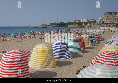 Biarritz, Frankreich - 22. Juli 2022: Farbenfrohe Sonnenschutzhütten am Grand Plage Strand in Biarritz Stockfoto