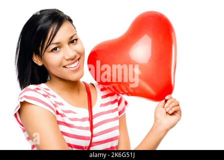 Sie hält dein Herz in ihrer Hand. Eine glückliche junge afrikanische Frau, die einen herzförmigen Ballon vor einem Studiohintergrund hält. Stockfoto