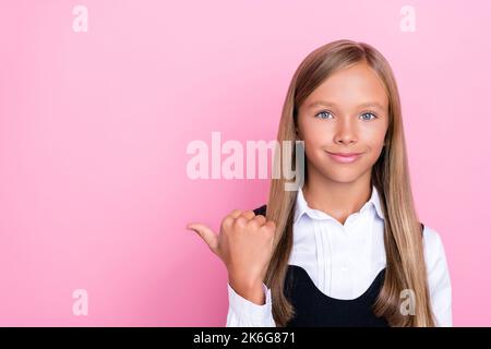 Foto von schönen smart fröhlich Schulmädchen mit geraden Frisur tragen Schuluniform Regie leeren Raum isoliert auf rosa Hintergrund Stockfoto