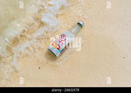 Koh Lipe, Thailand - 13.11.2019: Leeres Glas aus Limonadengetränk wird am Sandstrand in der Nähe des Meeres auf der Insel Ko Lipe, Thailand, aufgestellt. Glasmüll polluio Stockfoto