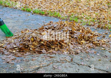 Im Herbst stapeln getrocknete Blätter, die auf Bürgersteigen aufgehäuft werden Stockfoto