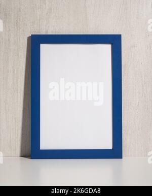 Vertikaler Fotorahmen im Regal. Leerer Diplomrahmen auf beigefarbenem Holz-Wandhintergrund. Bild-Frame-Modell. Leerer Diplomrahmen auf weißem Wandrahmen Stockfoto