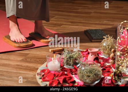 Frau, die auf dem Sadhu-Brett steht. Weibliche Füße auf Nagelbrett. Yoga, Meditation und Energiefluss üben. Stockfoto