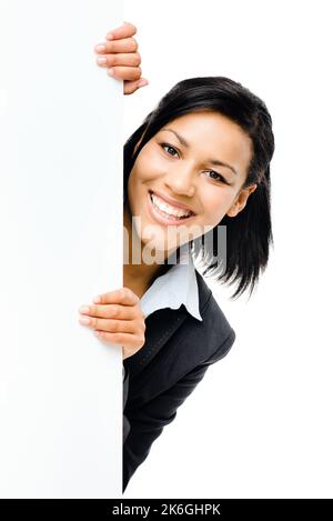 Blick hinter die Seiten. Eine junge Geschäftsfrau hinter einem leeren Plakat vor einem Studiohintergrund. Stockfoto