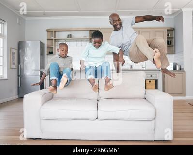 Eine Familie zu sein bedeutet, dass Sie ein Teil von etwas sind. Eine Familie, die zu Hause auf das Sofa springt. Stockfoto