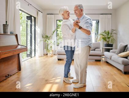 Fröhliche ältere Paare, die einen Tanz teilen und ihre Zeit zusammen genießen, während sie sich zu Hause verbinden. Glückliches Seniorenpaar, das die Lebensmomente genießt Stockfoto
