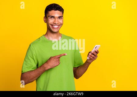 Foto von jungen gutaussehenden Studenten erfolgreichen Freiberufler Blogger halten Telefon zeigt okey Zeichen Lächeln nette Anzeige leeren Raum auf gelbe Farbe isoliert Stockfoto