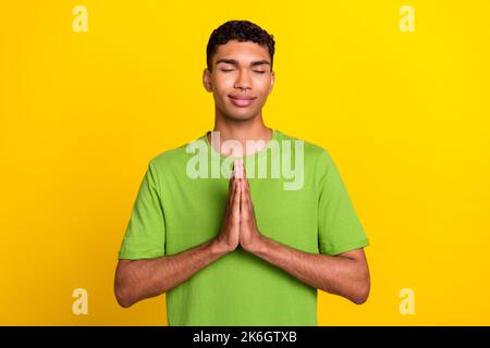 Foto von jungen attraktiven wunderschönen schönen positiven Kerl geschlossenen Augen verträumte gefaltete Palmen Meditation helfen isoliert auf gelben Hintergrund Stockfoto