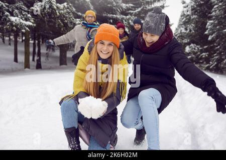 Lustige fröhliche paar weibliche und männliche Freunde, die Spaß im Freien mit Schnee im Winterwald haben. Stockfoto