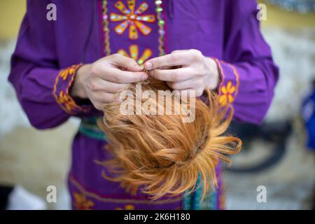 Ein Schauspieler oder Clown hält eine Bühnenperücke in seinen Händen. Stockfoto