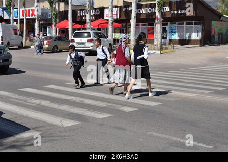 Cholpon-ATA, Kirgisistan - 17. September 2022: Erwachsene und Kinder überqueren an einer Fußgängerüberführung die Straße. Cholpon-ATA ist ein Ferienort im Norden Stockfoto