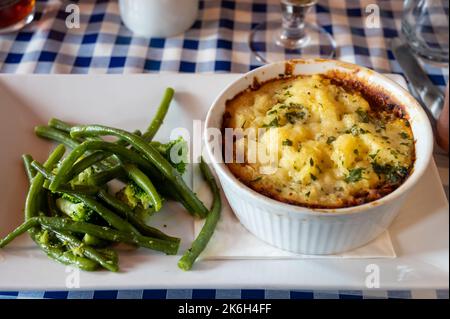 Gewürzte Linsen- und Pilzkuchen, langsam in Rotwein gekocht, mit Cheddar-Maische garniert und mit saisonalem Gemüse aus der Nähe serviert Stockfoto