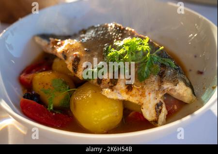 Provenzalische Küche, gegrilltes Weißfischfilet vom Seabarsch, serviert mit Kartoffeln, Tomaten und Bouillabaisse-Fischjus im französischen Restaurant Stockfoto